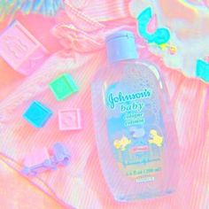 a bottle of johnson's baby cologne sitting on top of a pink blanket next to toys