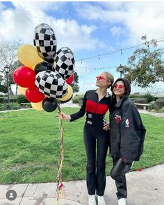 two women standing next to each other with balloons in the shape of checkered balls