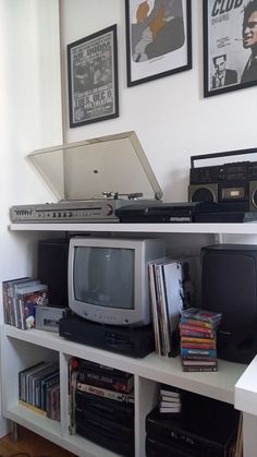 there is a tv, laptop and other electronics on the shelf in this room with pictures above it