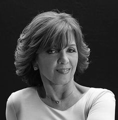 a black and white photo of a woman with her arms crossed looking at the camera