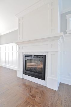 an empty living room with a fireplace and white wainscots on the walls