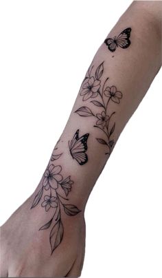 a woman's arm with flowers and butterflies on it, while she is holding the wrist