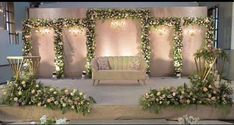 a stage set up for a wedding with flowers and greenery