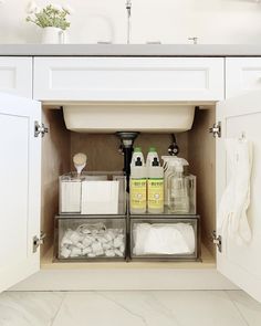 an open cabinet with cleaning products and other items in the bottom drawer, on top of a white countertop