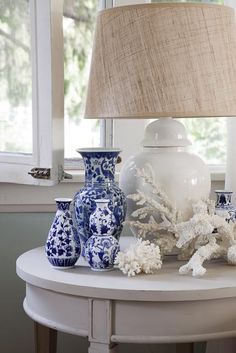 blue and white vases sit on a table next to a lamp