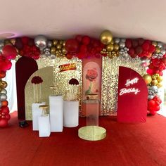 a red carpeted area with balloons and decorations on the wall, along with white pedestals