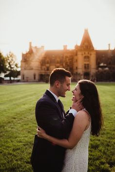 a bride and groom standing in front of a large building with grass on the ground