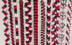 red, white and black ribbons hanging on the wall with hearts attached to each ribbon