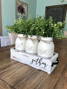 three mason jars with greenery in them sitting on a wooden table