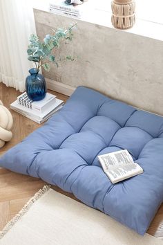 a blue futon mattress sitting on top of a wooden floor next to a window