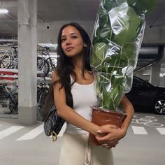 a woman holding a potted plant in a parking garage