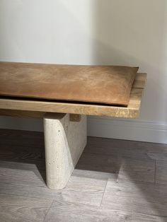 a wooden bench sitting on top of a hard wood floor next to a white wall