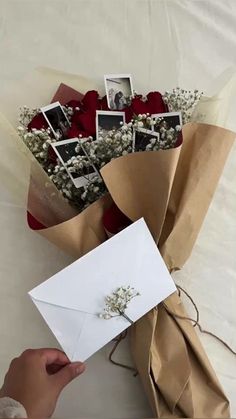 someone is holding a bouquet of flowers and an envelope with some pictures on the front