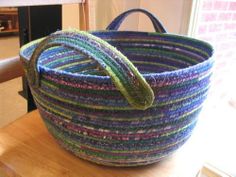 a multicolored basket sitting on top of a wooden table next to a window