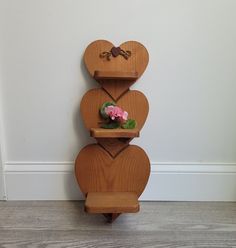 three wooden heart shaped shelves with flowers on them