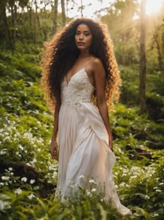 a woman with long hair standing in the woods wearing a white dress and looking off into the distance