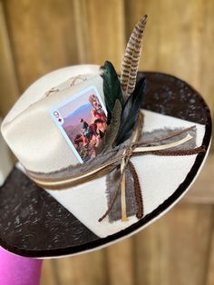 Rancher cowboy hat..🤠 Product description: felt cream wide brim/stitching/burned dot rays/leather fabric/cowboy card/feathers/multi-ribbon/torched top/suede lined brim Available now‼️ White Felt Hat For Western-themed Events, Kentucky Derby, White Felt Hat For Western-themed Events At Kentucky Derby, Handmade Western Fedora For Western-themed Events, Southwestern Curved Brim Felt Hat For Country Events, Southwestern Felt Hat With Curved Brim For Country Events, Handmade Western Fedora For Country Events, Rustic Fedora For Kentucky Derby And Country Events, Handmade Country Style Fedora For Western-themed Events, Rustic Wide Brim Felt Hat For Country Events