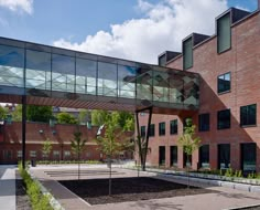 a building with a glass walkway leading to the front entrance and courtyard area on both sides