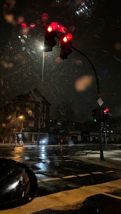 the traffic light is red at night in the city street with snow falling on it