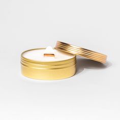 two gold and white candles sitting next to each other on top of a white surface