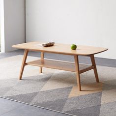 a wooden table with an apple on it in front of a white wall and carpet