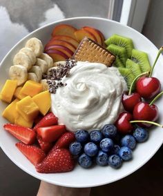 a white bowl filled with fruit, crackers and whipped cream on top of it