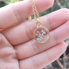 a person is holding a small glass pendant in their hand and it has flowers on it