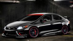 a black car with red rims parked in a garage