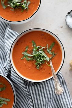 two bowls of tomato soup with herbs on top