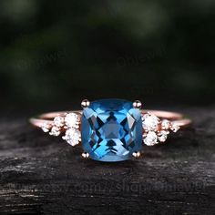 a blue topazte and diamond ring sits on a piece of wood