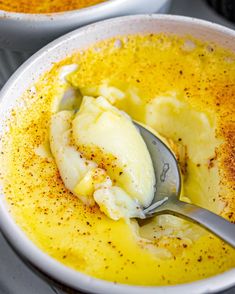 two white bowls filled with soup and some spoons