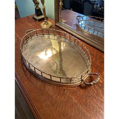 a large metal tray sitting on top of a wooden table next to a mirror and lamp