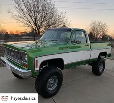 a green and white truck parked on top of a driveway