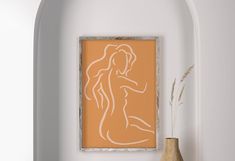 an orange and white painting on a wall next to a vase with flowers in it