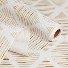 a white and gold wallpaper with wavy lines on the surface, as well as a roll of tape