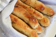 some bread sticks are sitting on a white plate with a blue and white dish towel