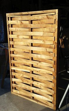 a large wooden slatted screen sitting on top of a cement floor next to a building