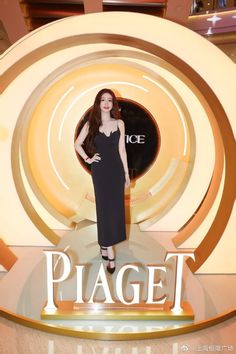 a woman standing in front of a sign that says piagett