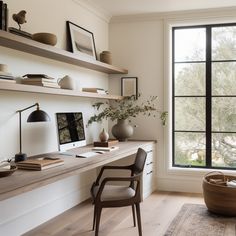 a home office with a desk, chair and large window overlooking the trees in the distance