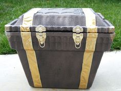 a large trunk sitting on top of a cement slab in the grass with yellow straps around it