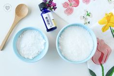 two blue bowls filled with white powder next to a wooden spoon and flower print towel