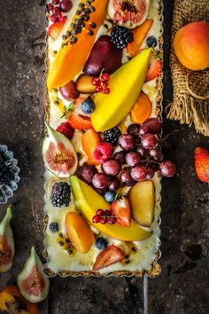 an assortment of fruit is on top of a bread with other fruits and vegetables around it