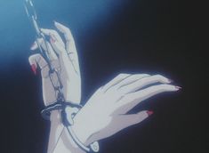 a woman's hand with red nail polish holding a chain