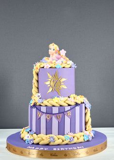 a three tiered cake with princess figurines on top and purple icing