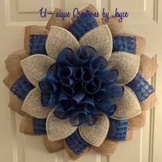 a burlap and blue flower is hanging on the front door