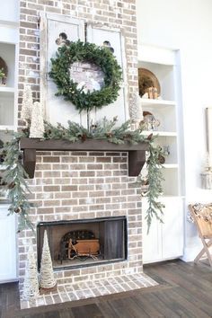 a fireplace decorated for christmas with greenery and wreath