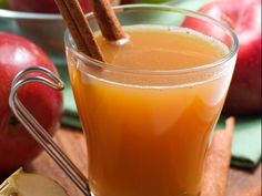 an apple cider with cinnamon sticks and apples in the background