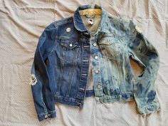 two denim jackets sitting on top of a bed next to each other, one worn and the other faded