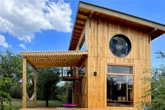 a small wooden house with a circular window on the side and a porch attached to it