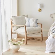 a white chair sitting next to a bed on top of a hard wood floor